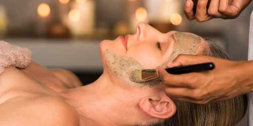 esthetician giving a client a facial mask